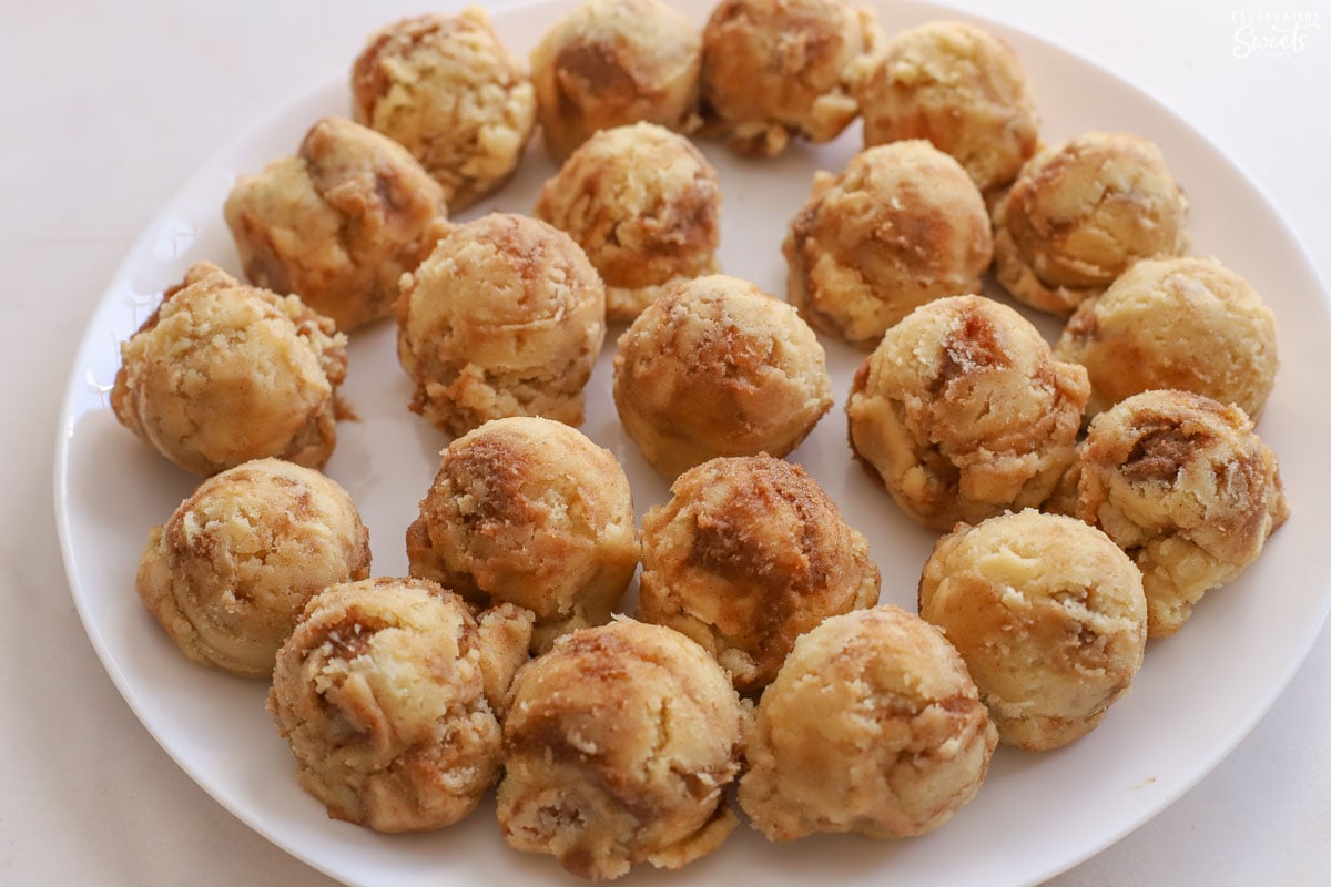 Scoops of cinnamon roll cookie dough on a white plate.