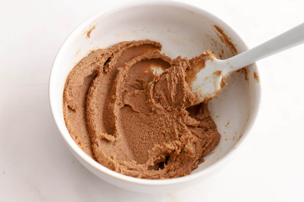 Cinnamon brown sugar butter in a white bowl with a small rubber spatula.