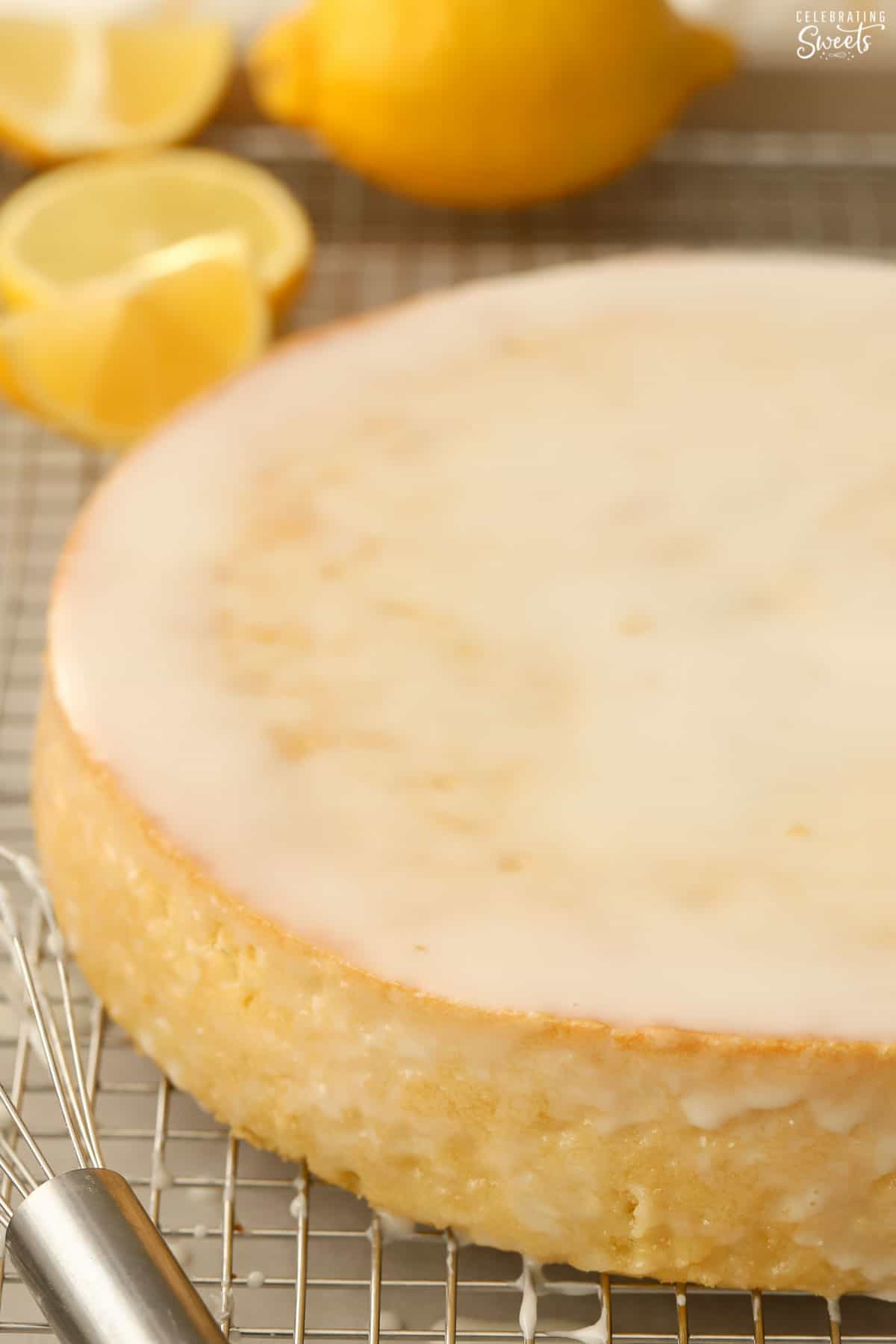 Lemon olive oil cake topped with white icing on a metal rack.