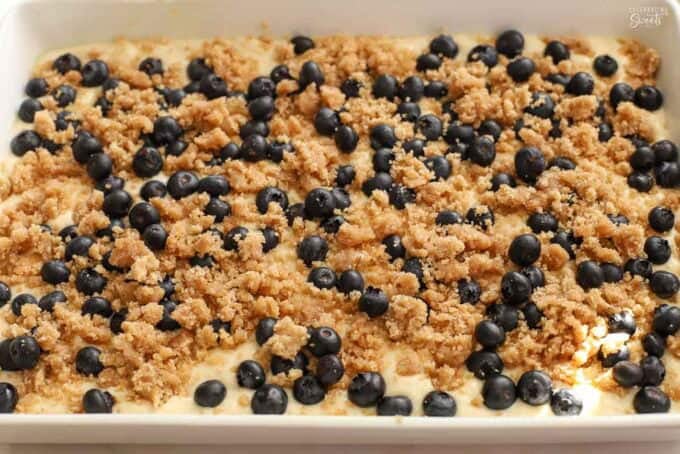 Unbaked pancake casserole topped with blueberries and a crumb topping in a white baking dish.