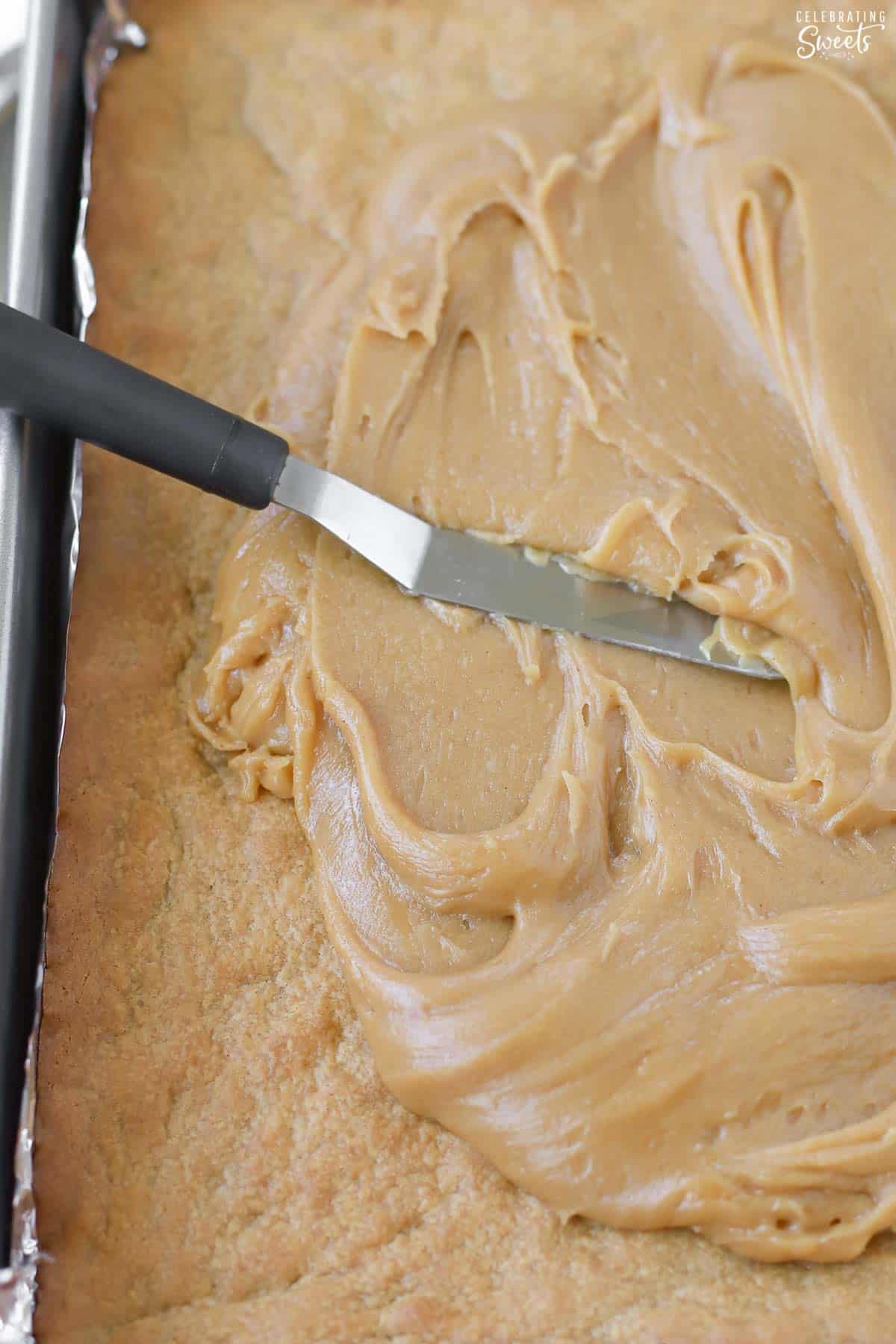 Peanut butter icing being spread on peanut butter bars.