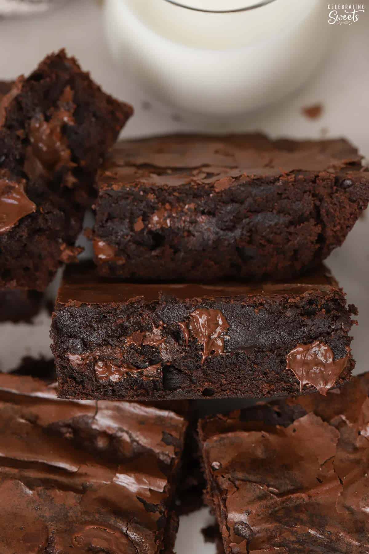 Closeup of a fudgy brownie with a glass of milk in the background.