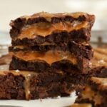 Stack of three caramel brownies on parchment paper.