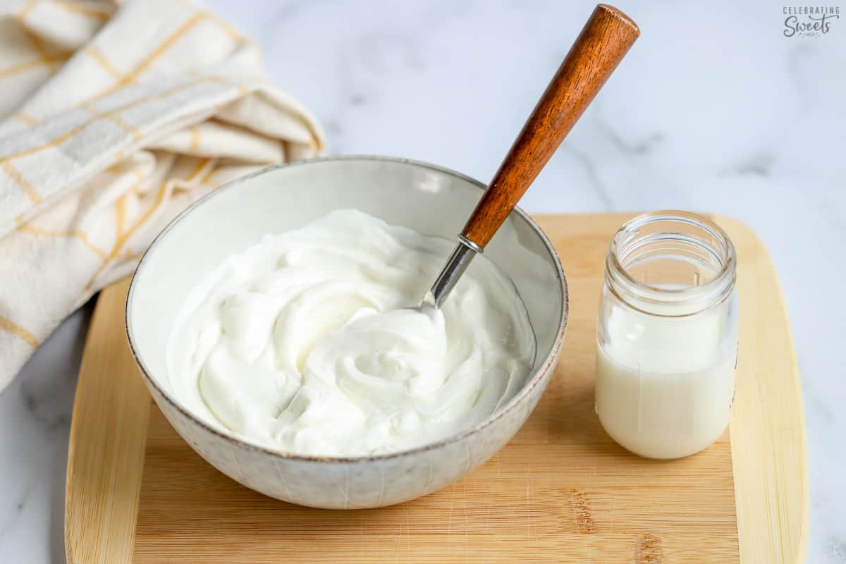 Yogurt in a bowl next to a jar of milk for making buttermilk substitute.