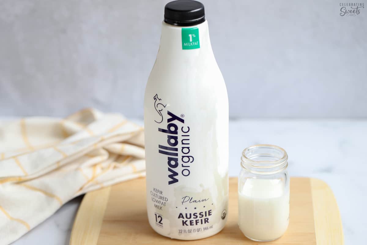 Kefir next to a jar of milk on a wooden board for making buttermilk substitute.