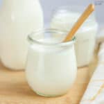 Jar of buttermilk substitute on a wooden board with a wooden spoon.