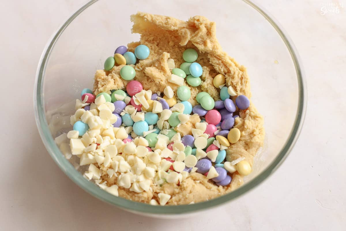Pastel M&M's and white chocolate chips in a bowl of cookie dough.