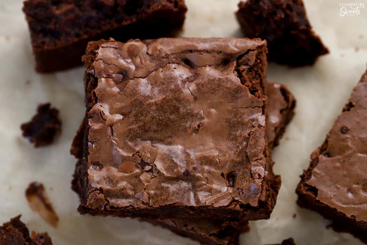 Square brownie on top of another brownie on a piece of parchment paper.