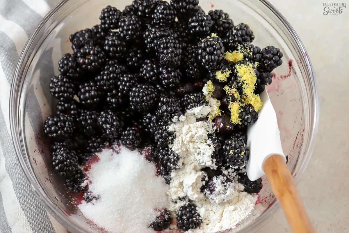 Blackberries, lemon zest, sugar, and flour in a glass bowl.