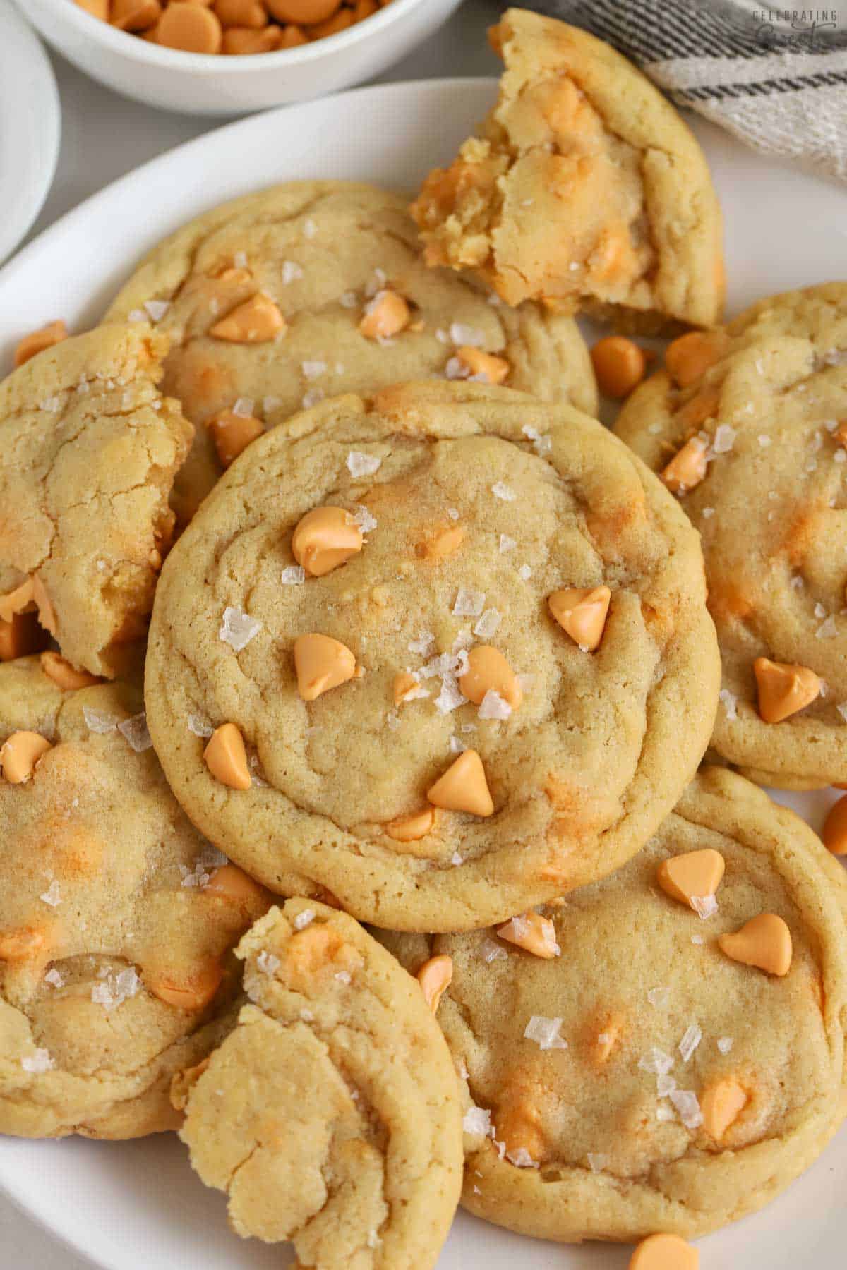 Butterscotch cookies topped with flaky sea salt on a white plate.