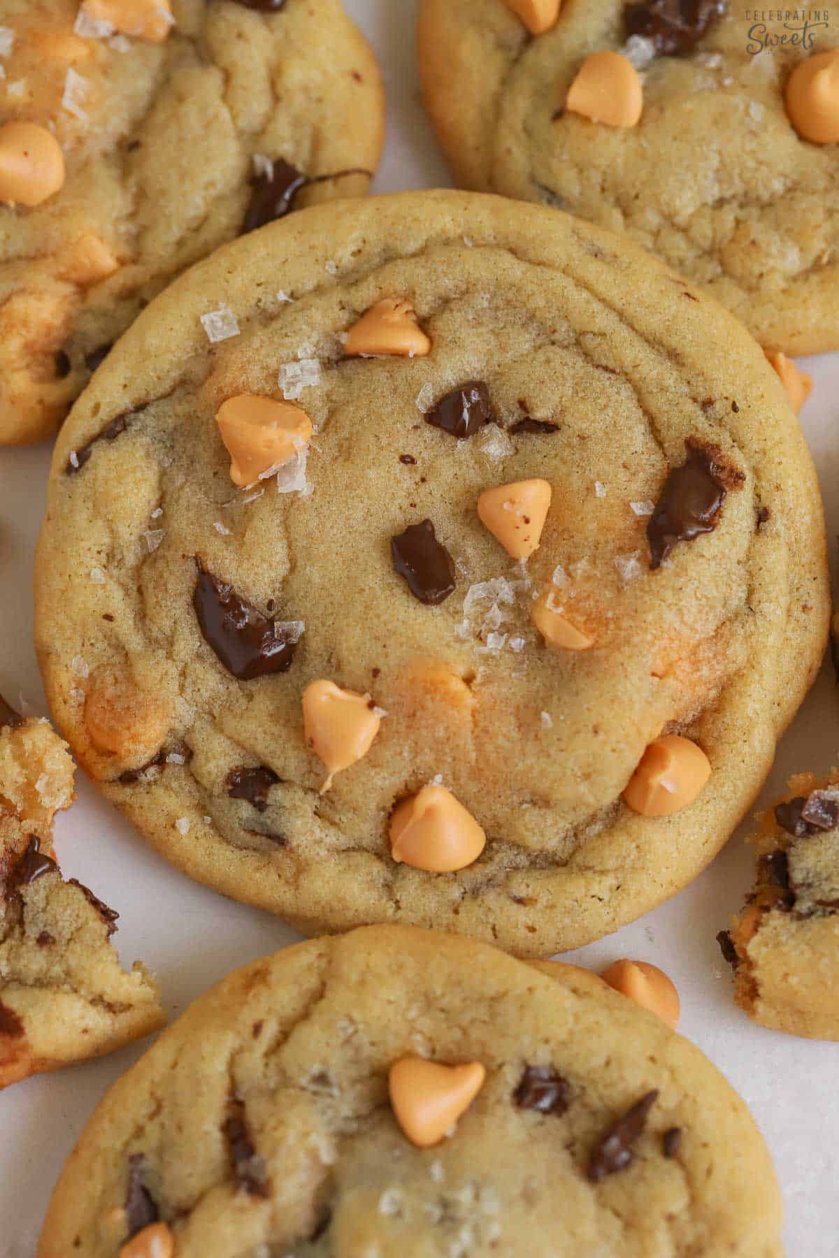 Chocolate chip and butterscotch cookie topped with flaky sea salt on parchment paper.
