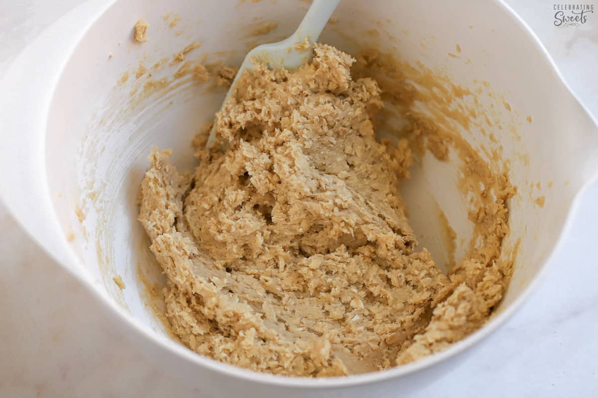 Oatmeal cookie dough in a whote bowl.