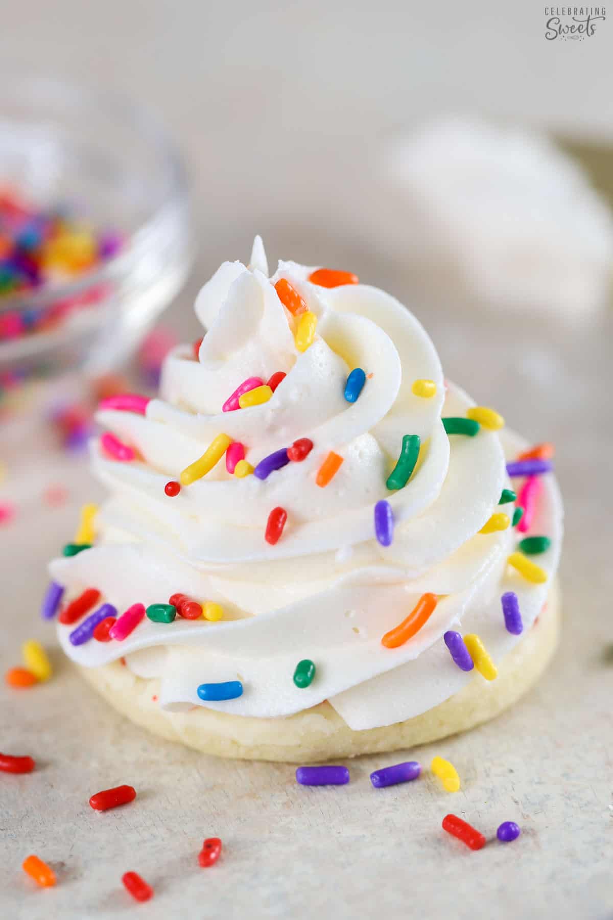 Vanilla buttercream frosting on a cookie topped with rainbow sprinkles.