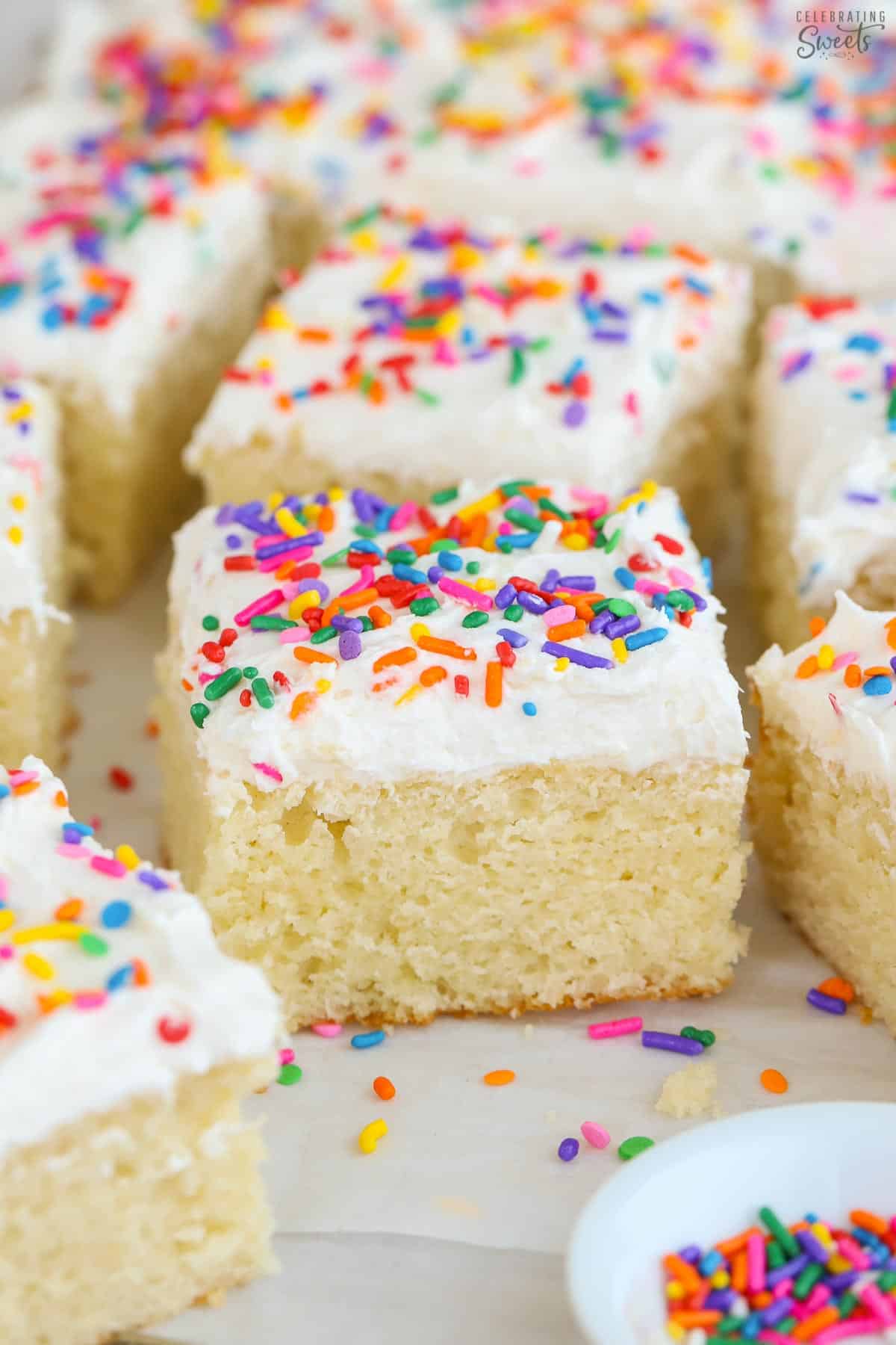 Vanilla sheet cake topped with vanilla buttercream frosting and rainbow sprinkles.