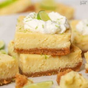 Stack of two key lime pie bars topped with whipped cream.