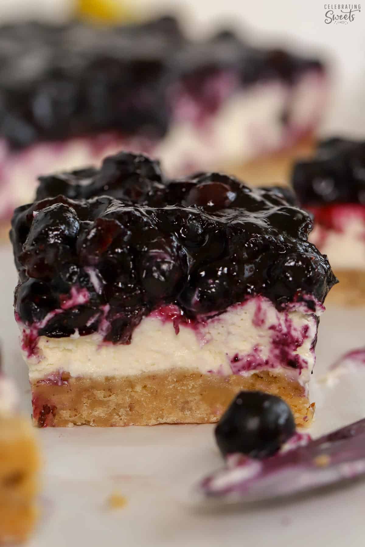 Slice of blueberry dessert bar next to a knife.
