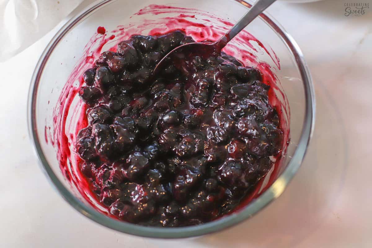 Blueberry sauce in a glass bowl with a spoon.