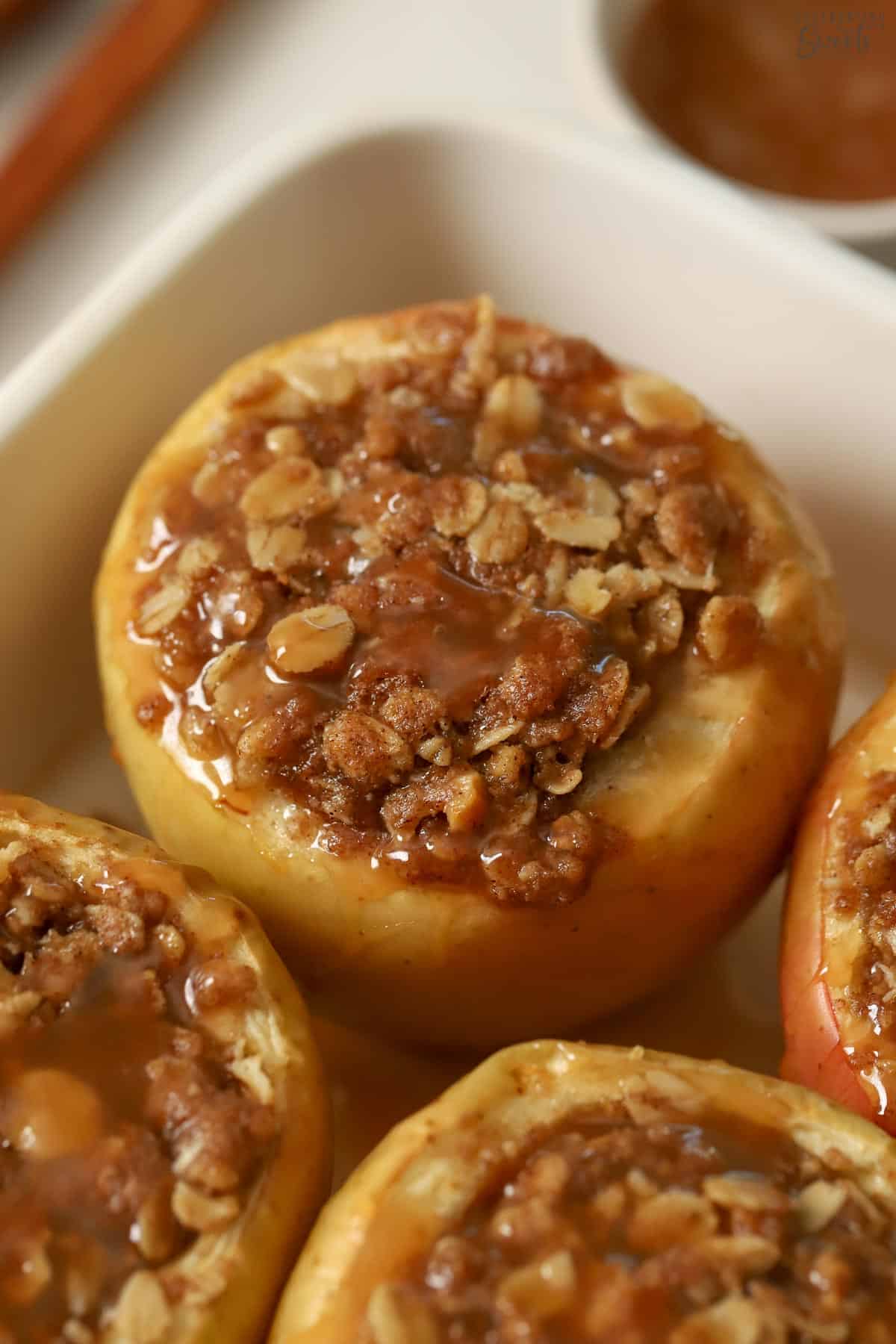 Baked apples topped with caramel in a baking dish.