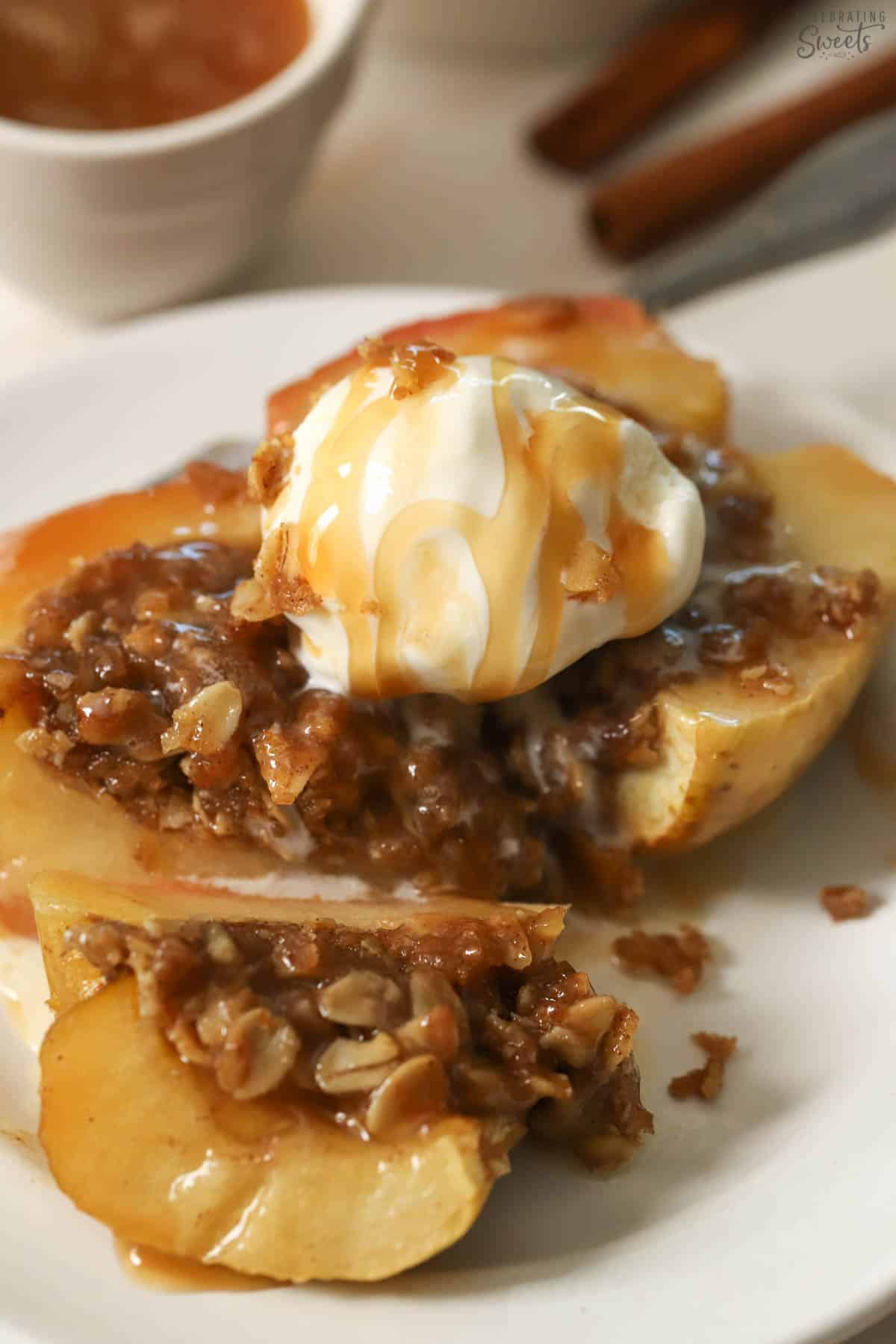 Baked apple topped with ice cream and caramel sauce on a white plate.