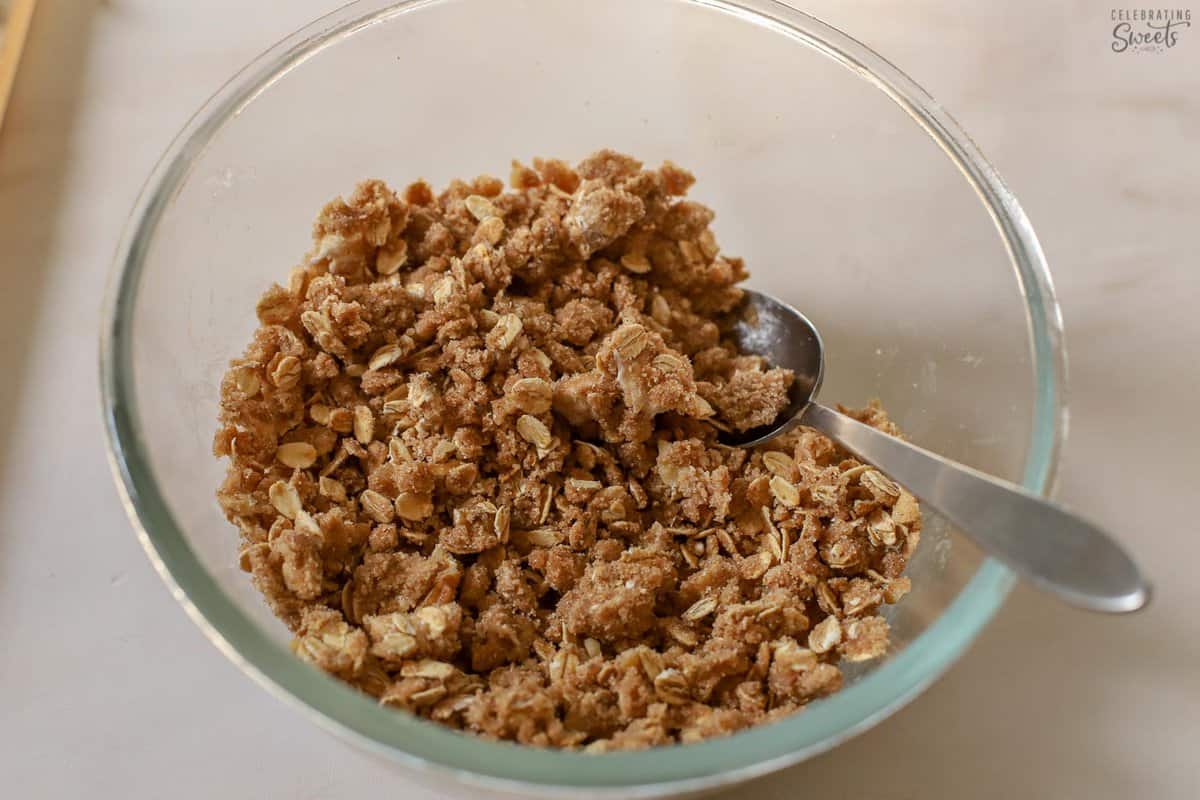 Baked apple topping in a glass bowl with a spoon.