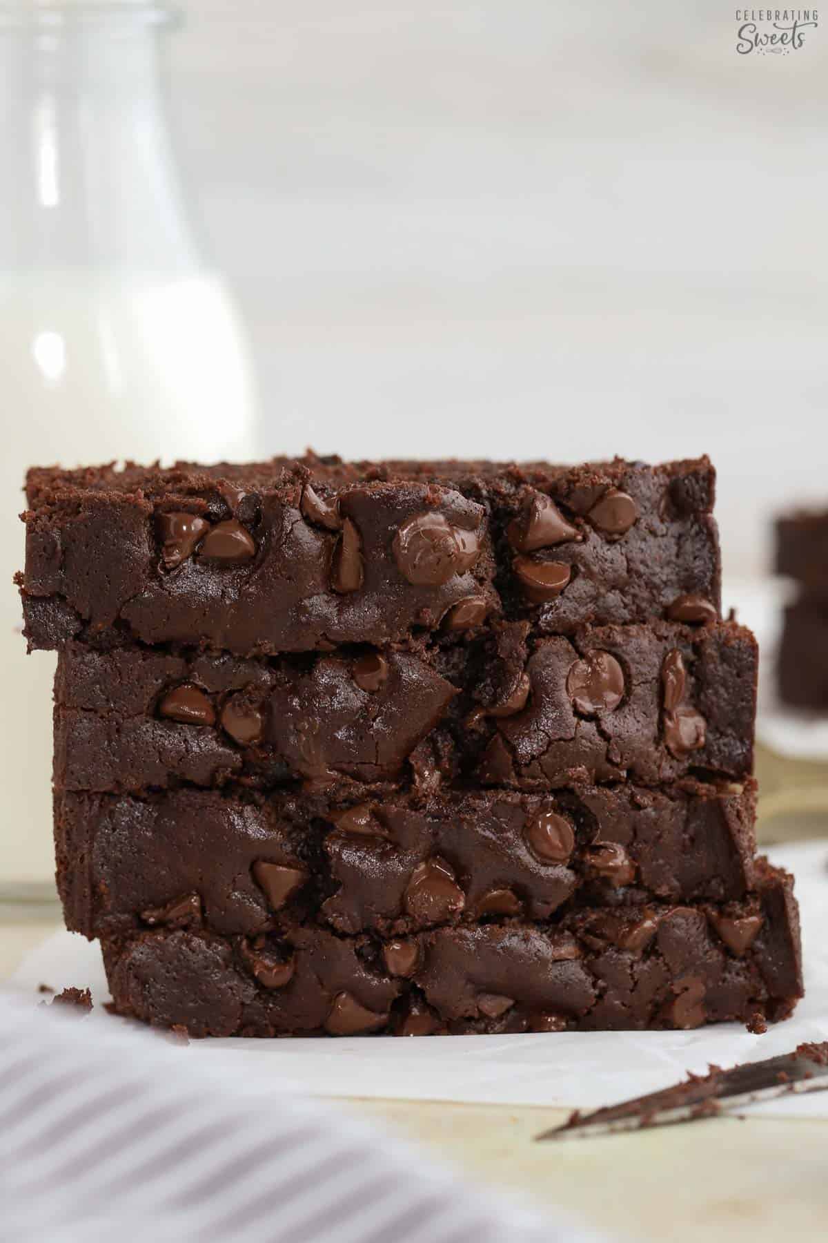 Stack of four slices of chocolate zucchini bread with a jar of milk in the background.