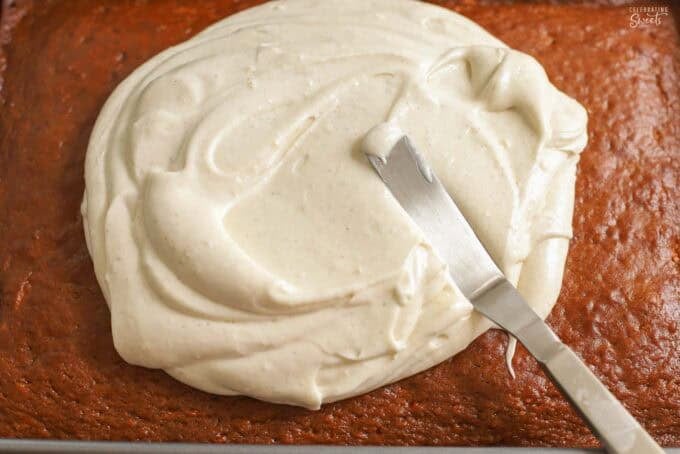 Cinnamon cream cheese frosting being spread on an applesauce cake.