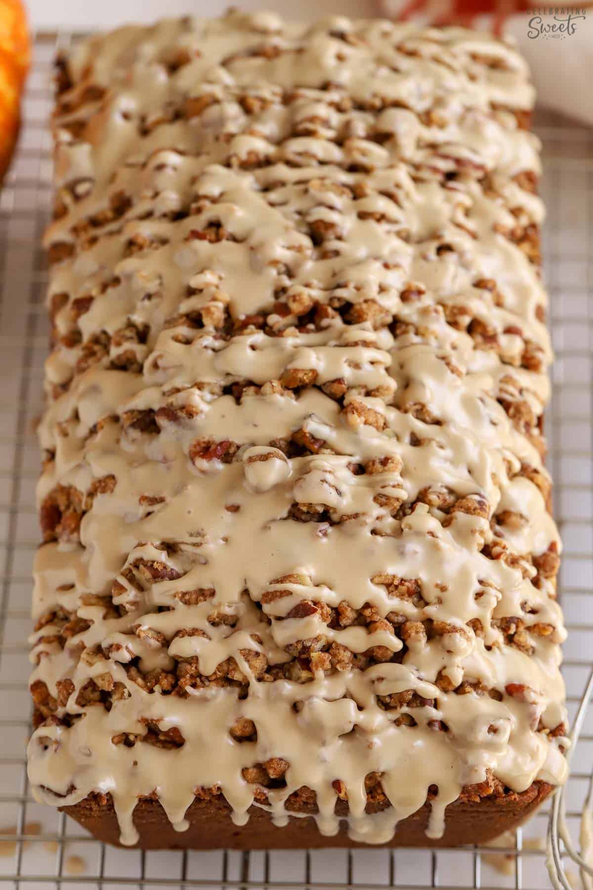 Loaf of pumpkin bread topped with icing on a rack.