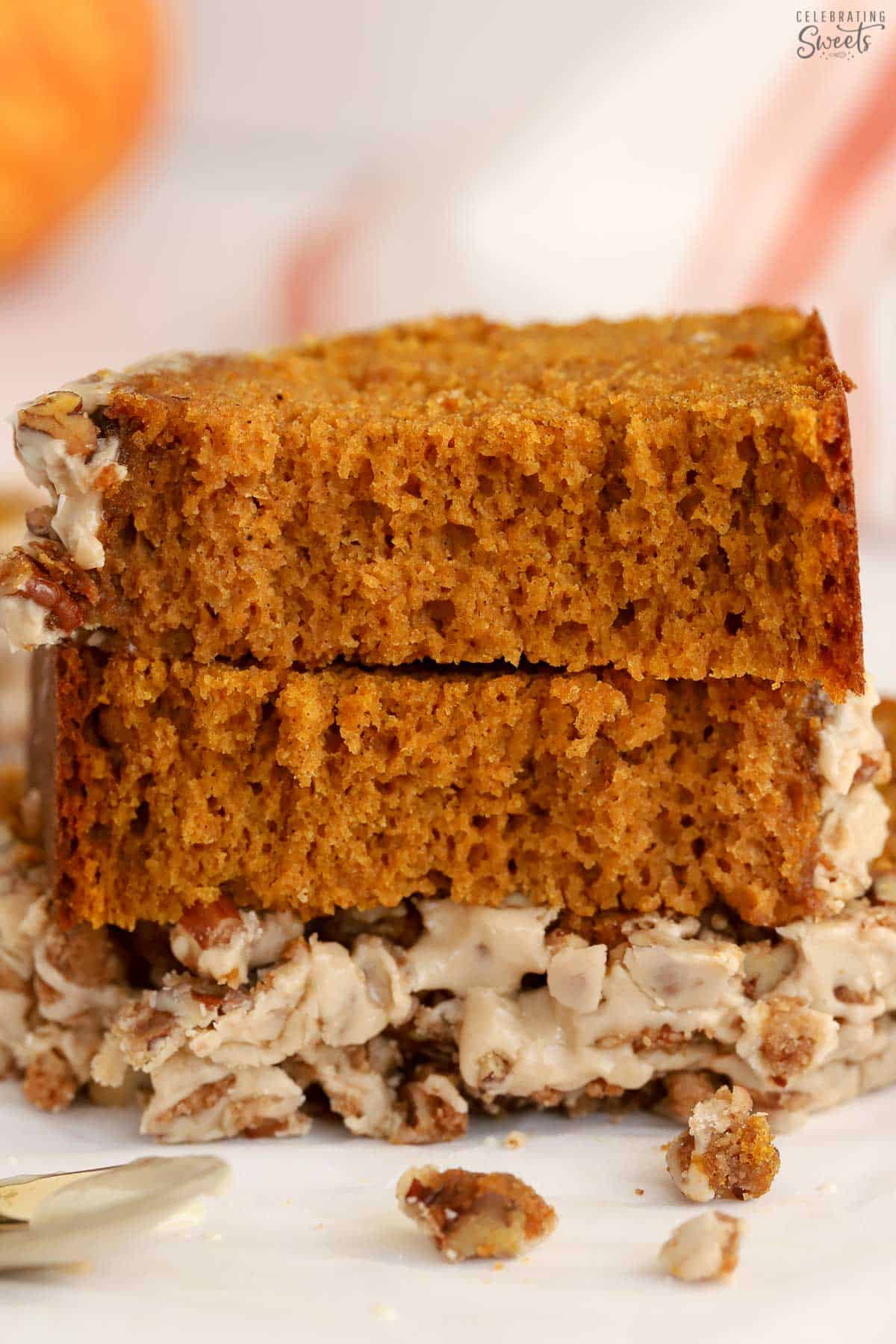Pieces of pumpkin bread stacked on top of each other next to a gold spoon.
