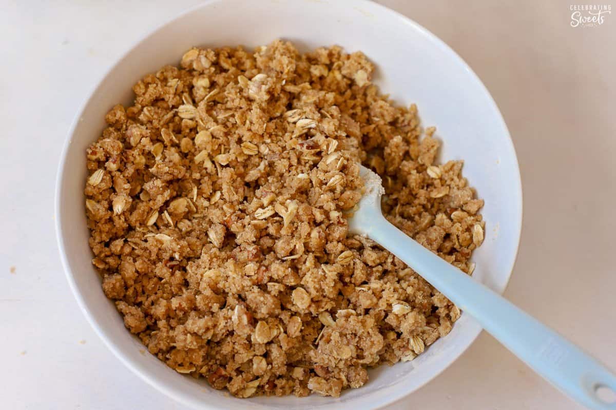 Pumpkin crisp topping in a white bowl with a grey spatula.