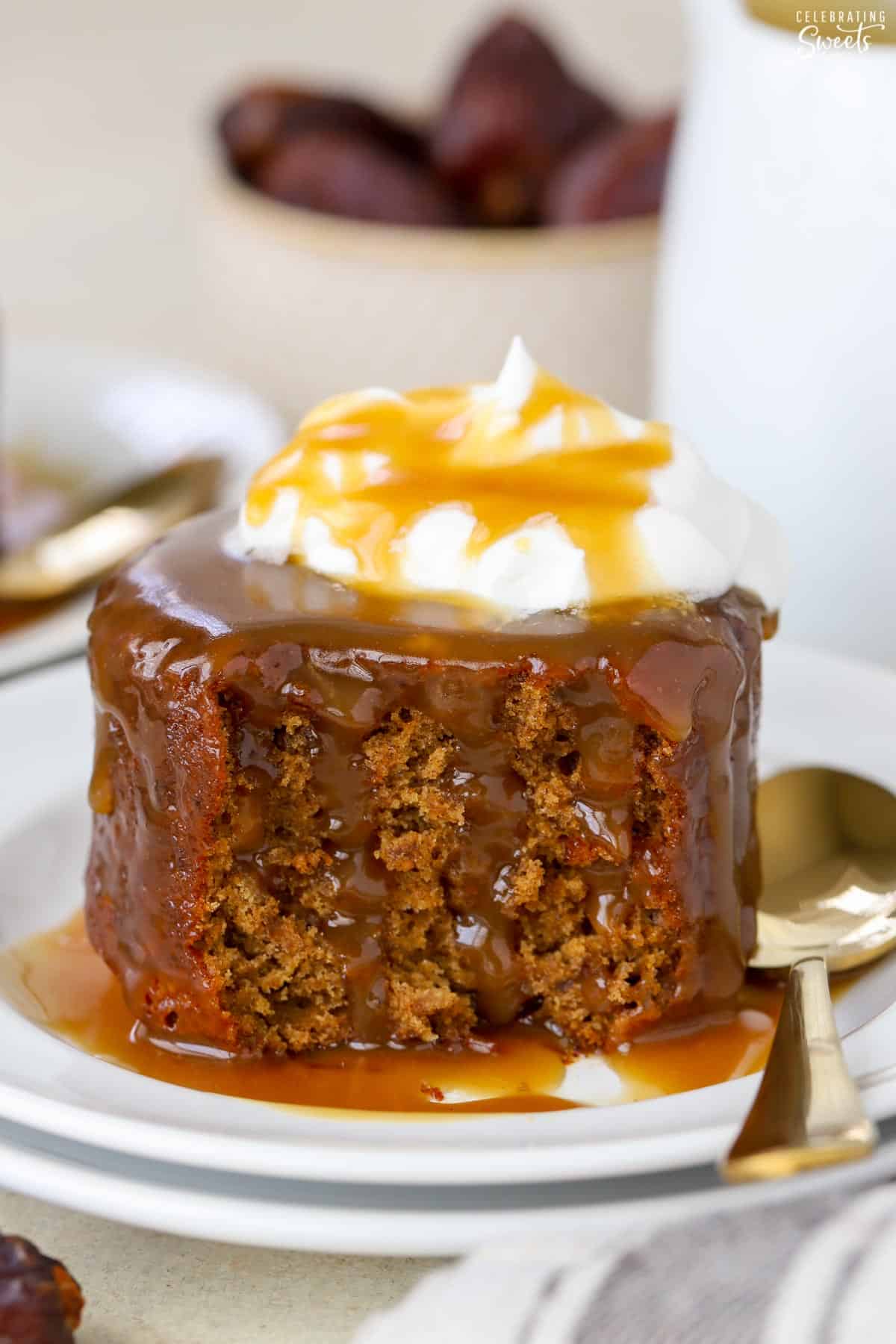 Sticky toffee pudding on a white plate with a gold fork.