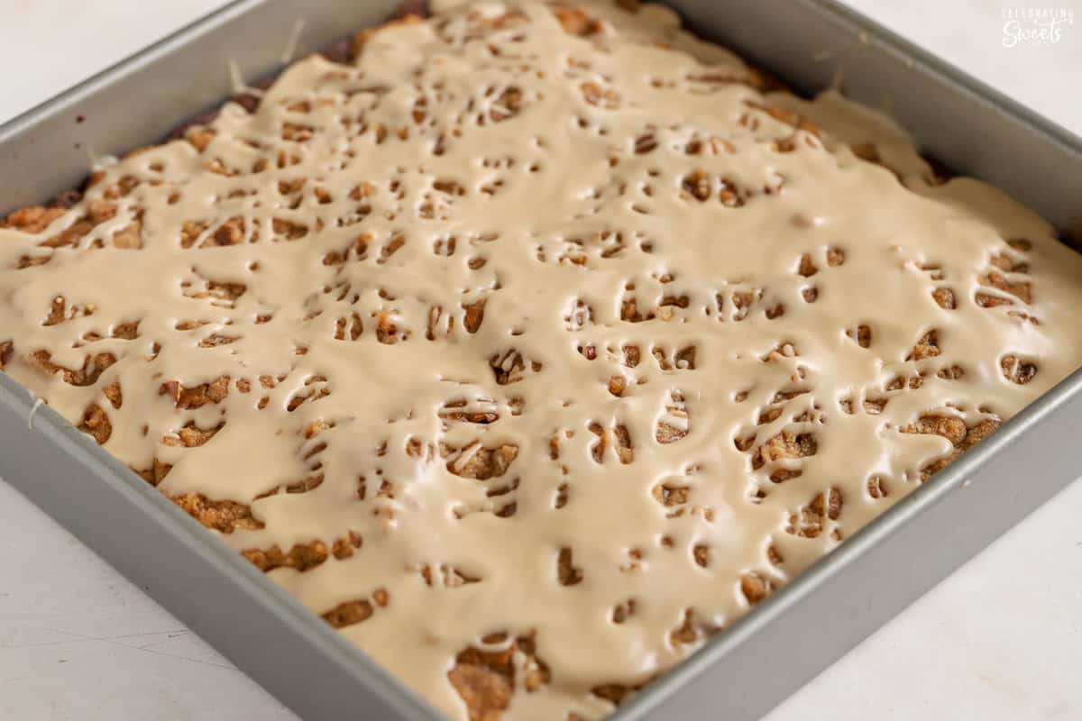 Gingerbread cake in a square pan topped with icing.