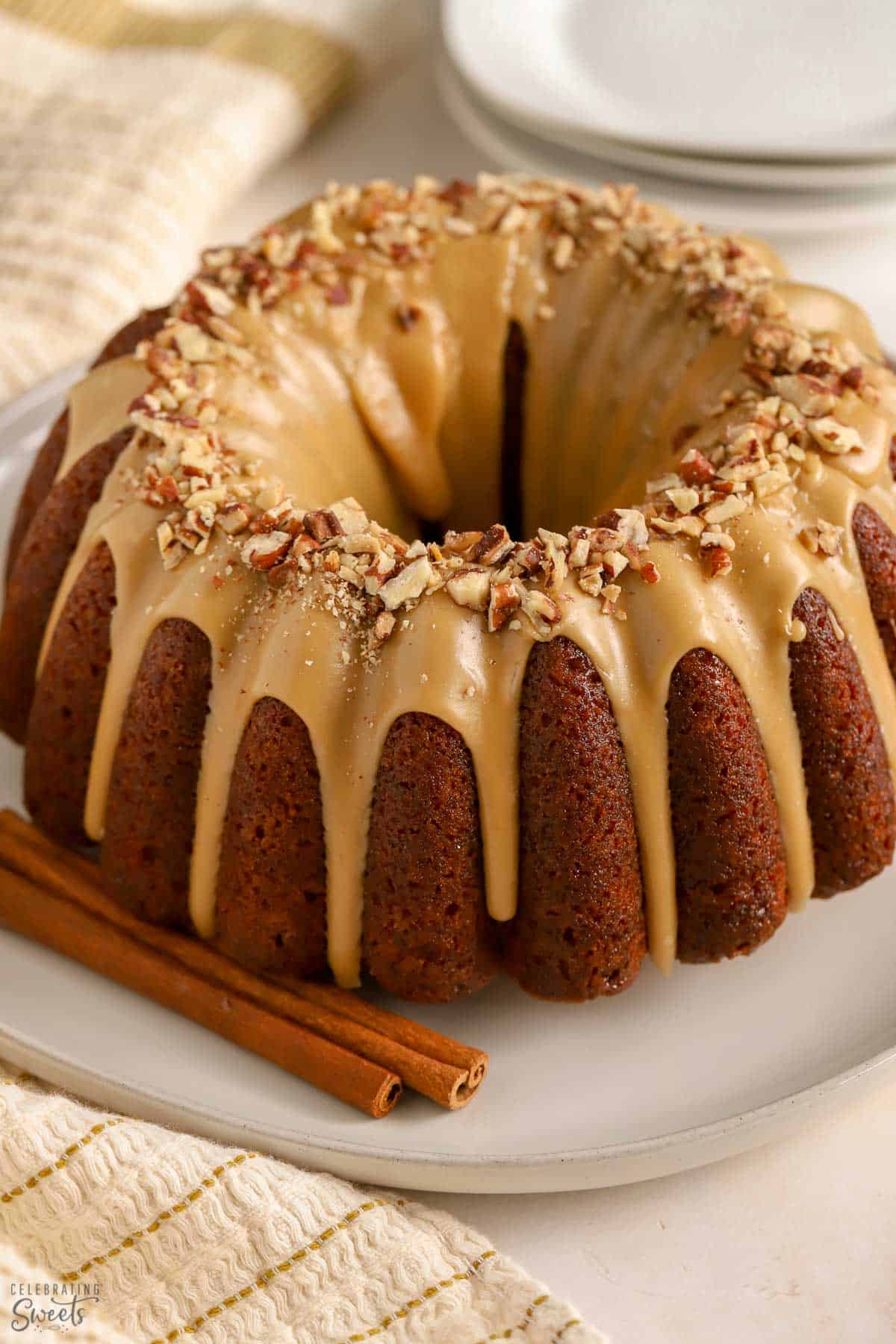 Bundt shaped spice cake covered in a maple glaze and topped with pecans.