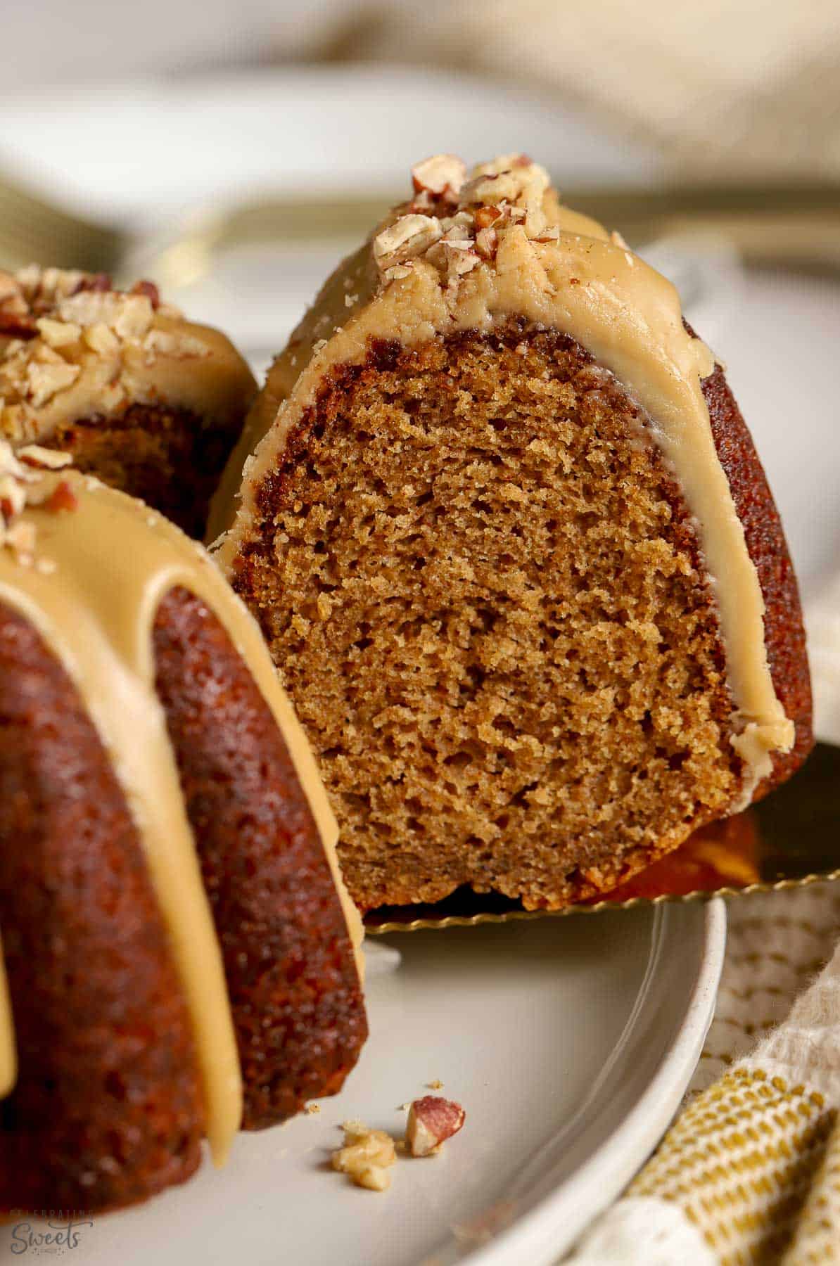 Closeup of a spice cake on a grey plate with a gold spatula.