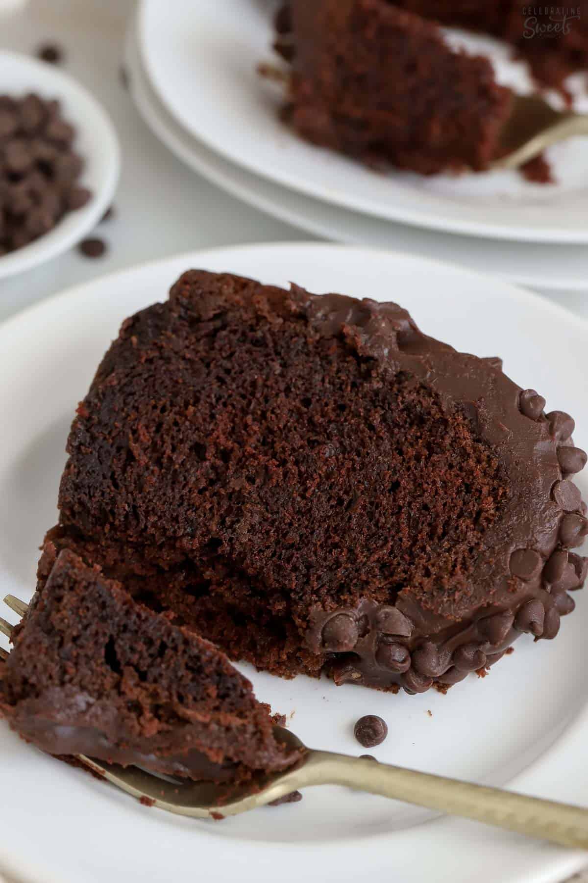 Slice of chocolate bundt cake on a white plate with a gold fork.