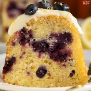 Closeup of a slice of lemon blueberry bundt cake on a white plate.