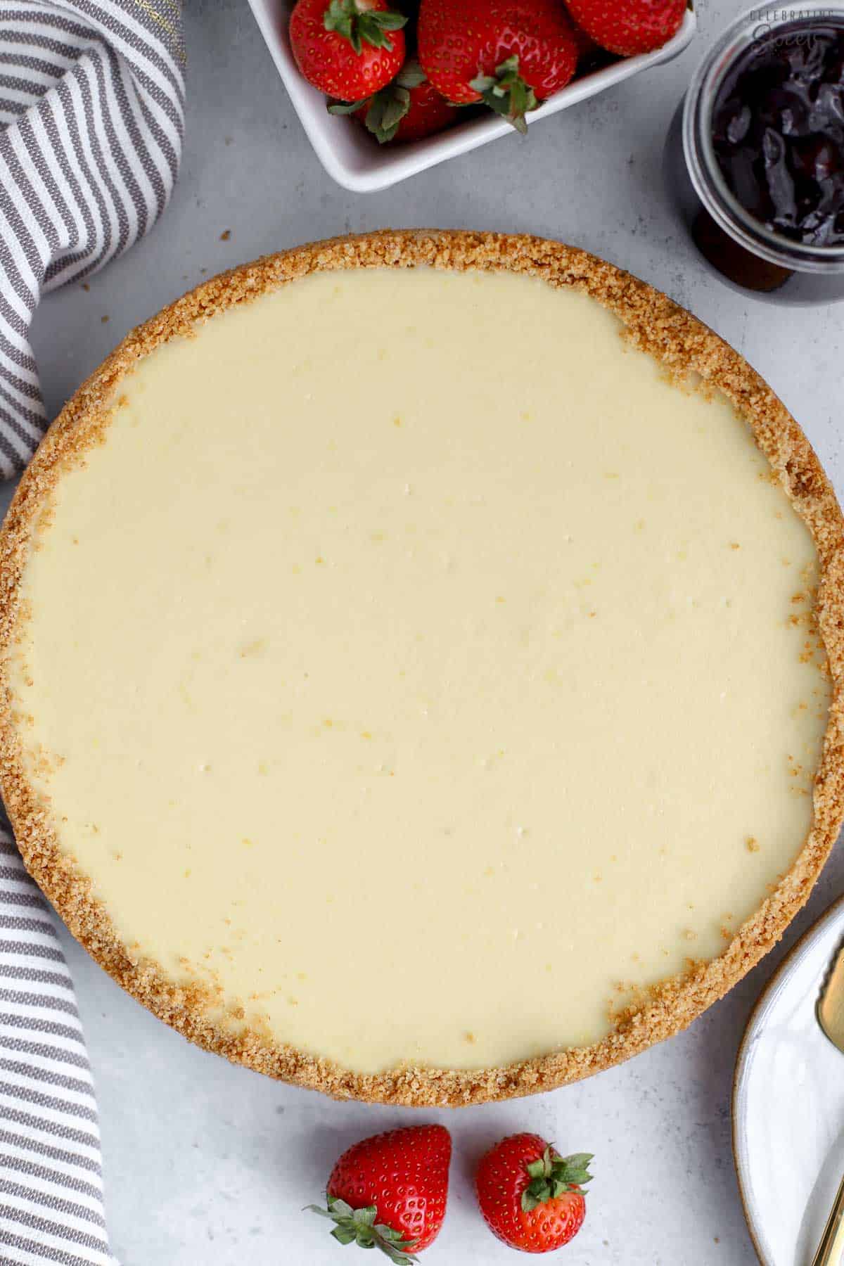 Overhead photo of Greek yogurt cheesecake on a grey table with a basket of strawberries,