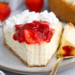 A slice of Greek yogurt cheesecake on a grey plate with a gold fork.