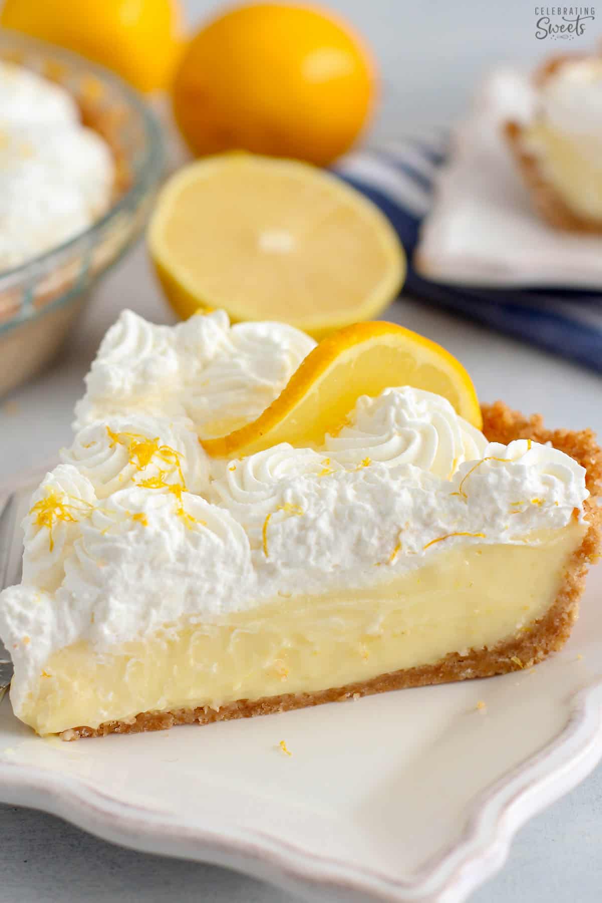 Slice of lemon cream pie on a white plate with a silver fork.