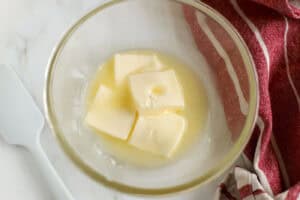 Softened slightly melted butter in a glass bowl next to a red napkin.