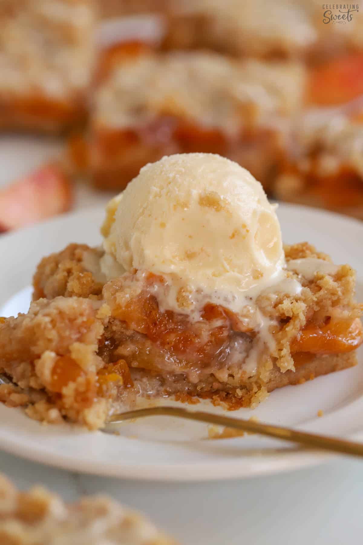 Peach bar on a white plate topped with vanilla ice cream.