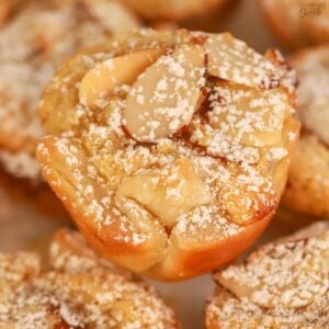 Closeup of an almond croissant bite dusted with powdered sugar.
