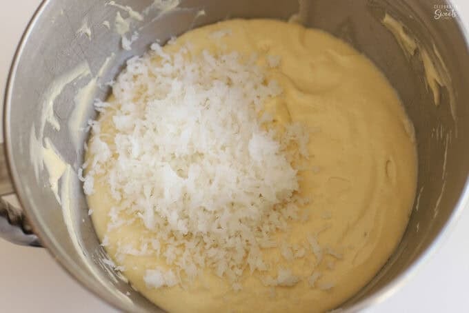 Coconut cake batter and shredded coconut in a stainless bowl.