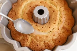 Syrup being spooned into holes on a bundt cake.