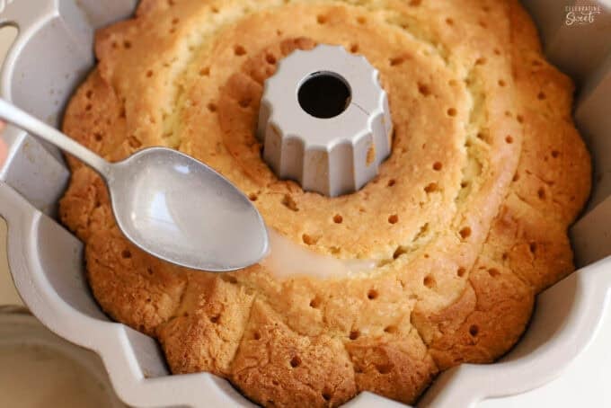 Syrup being spooned into holes on a bundt cake.