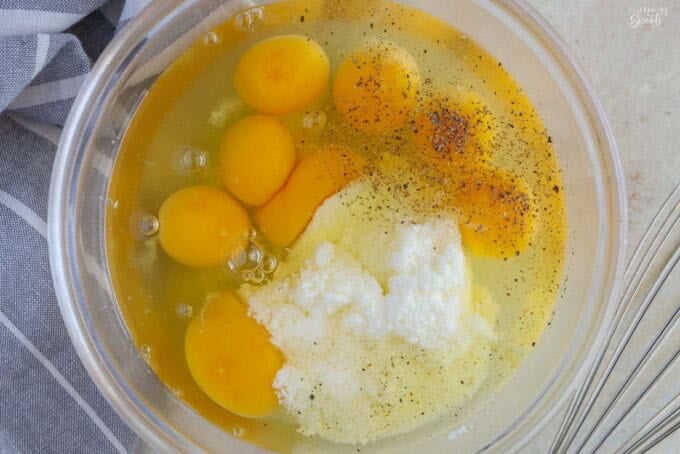 Eggs and cottage cheese in a glass bowl next to a blue striped napkin.