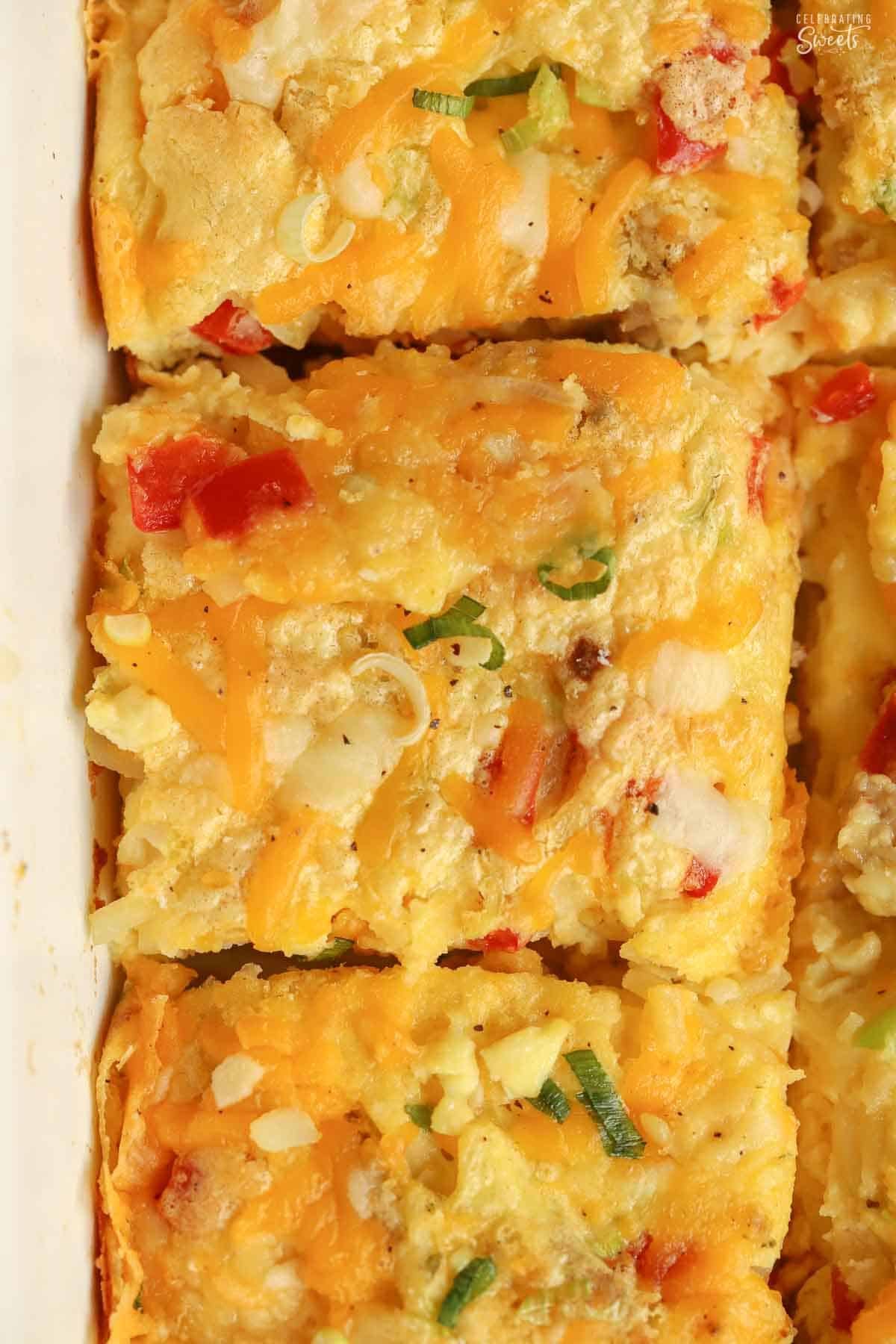 Egg casserole, sliced into squares, in a white baking dish.