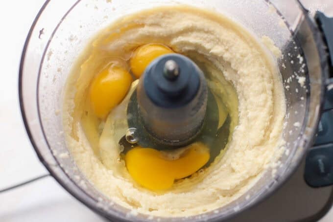 Eggs, butter, and sugar in the bowl of a food processor.