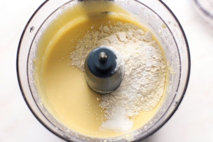 Cake batter and flour in the bowl of a food processor.