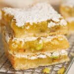 Stack of three lemon pistachio bars on a wire rack.