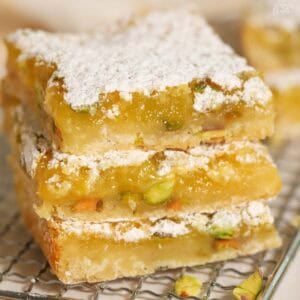 Stack of three lemon pistachio bars on a wire rack.